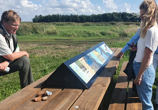 Bezoekers bij een informatiepaneel met uitzicht op het landschap