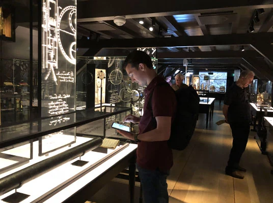 Een bezoeker gebruikt de app naast de objecten in de tentoonstelling.